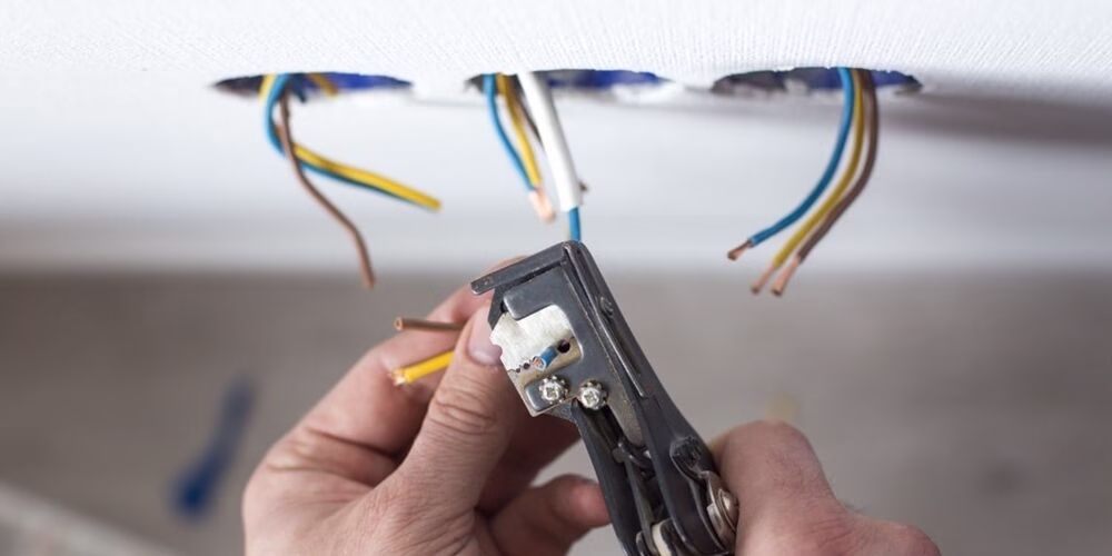 Eletricista cortando fios elétricos na parede